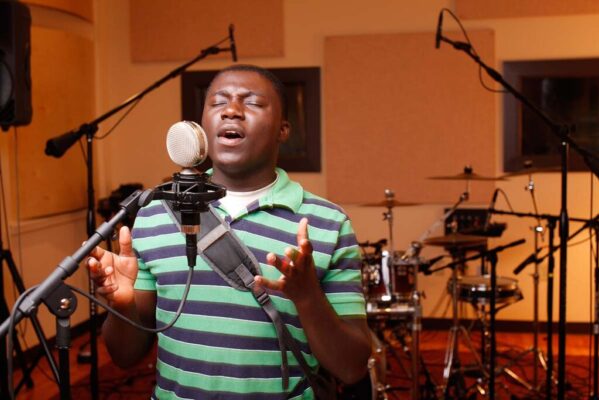 A young man singing into a microphone with his eyes closed