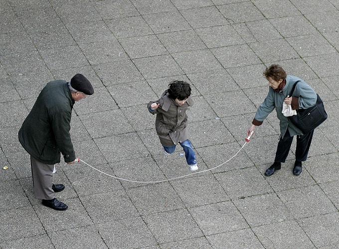 Two elderly people playing jump rope with a child