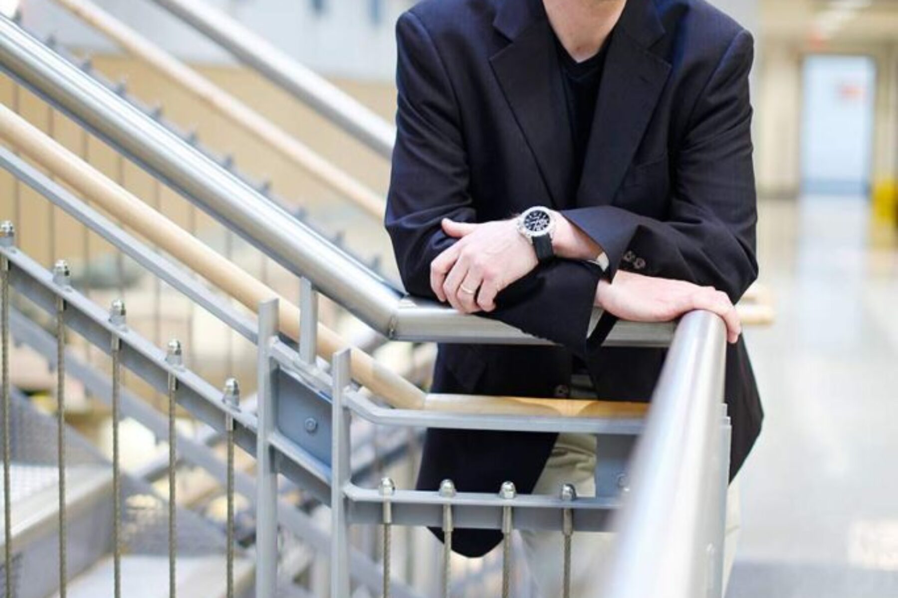 A man leaning on to the rail of a staircase and posing