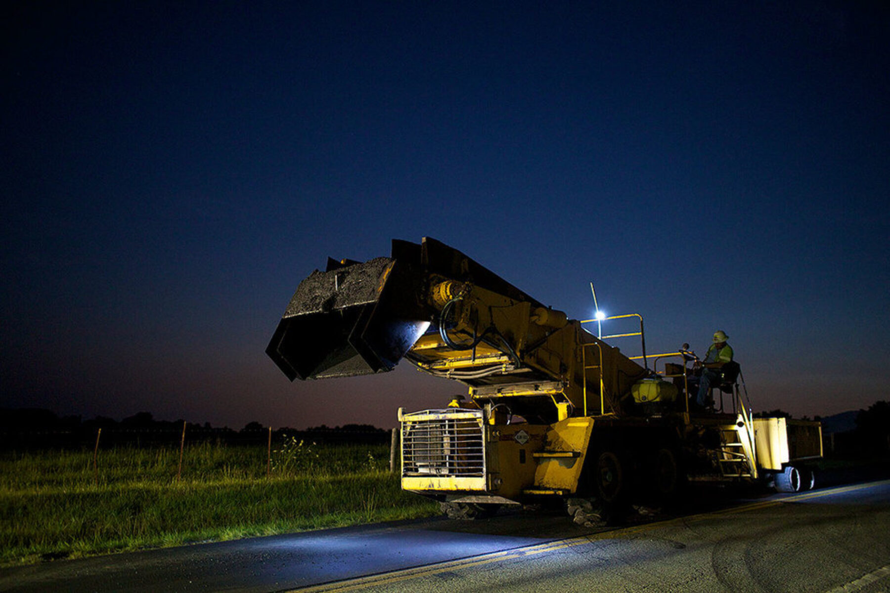 A man operating a large machine to operate on the roadway