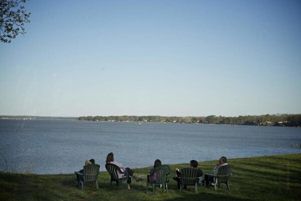 A group of individuals sitting on lawn chairs looking over a body of water