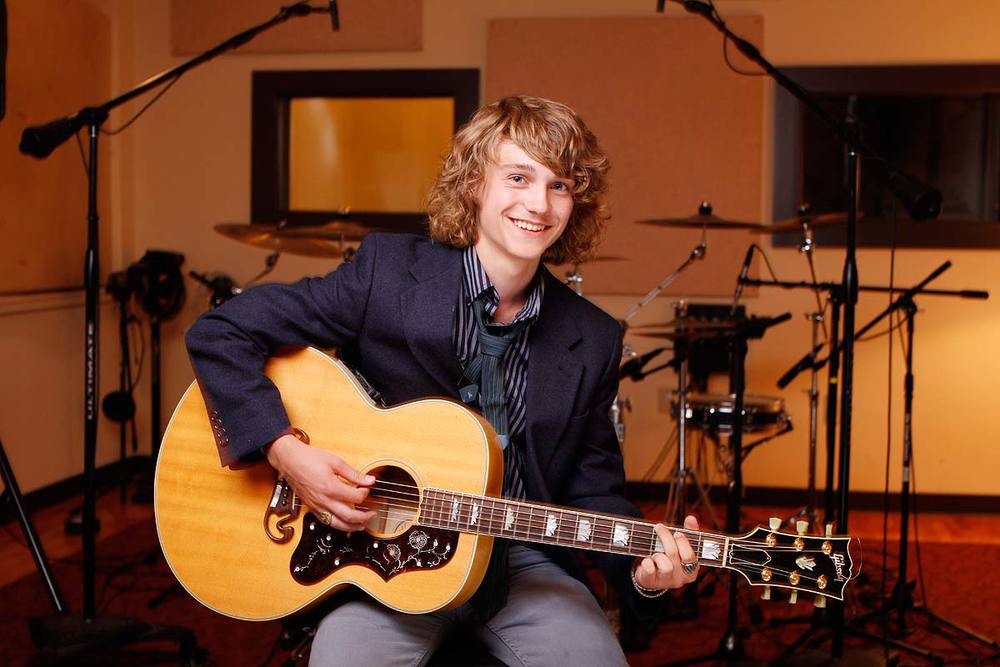 A young man holding a guitar posing for a photo