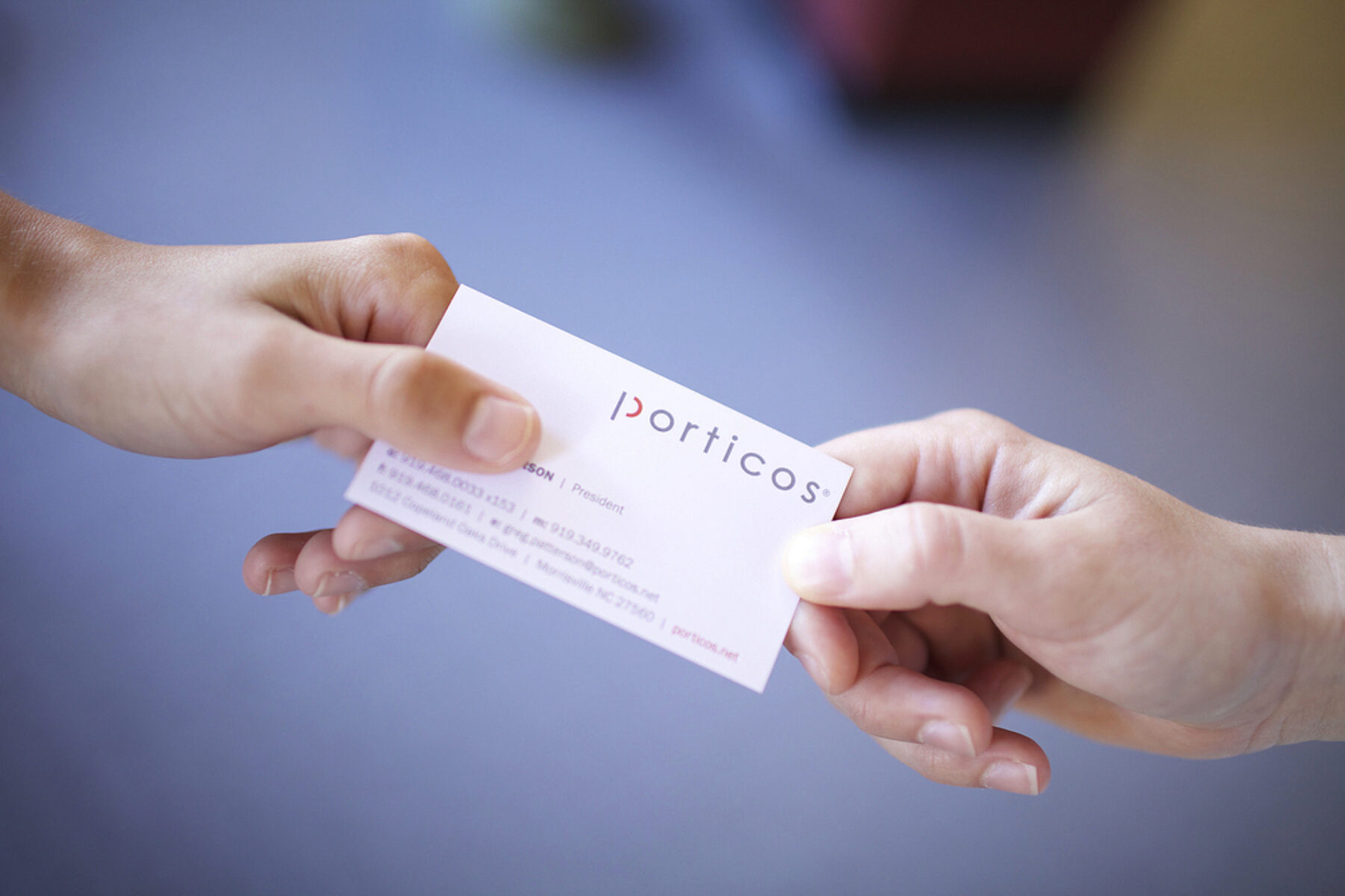 Two people exchanging a Porticos business card