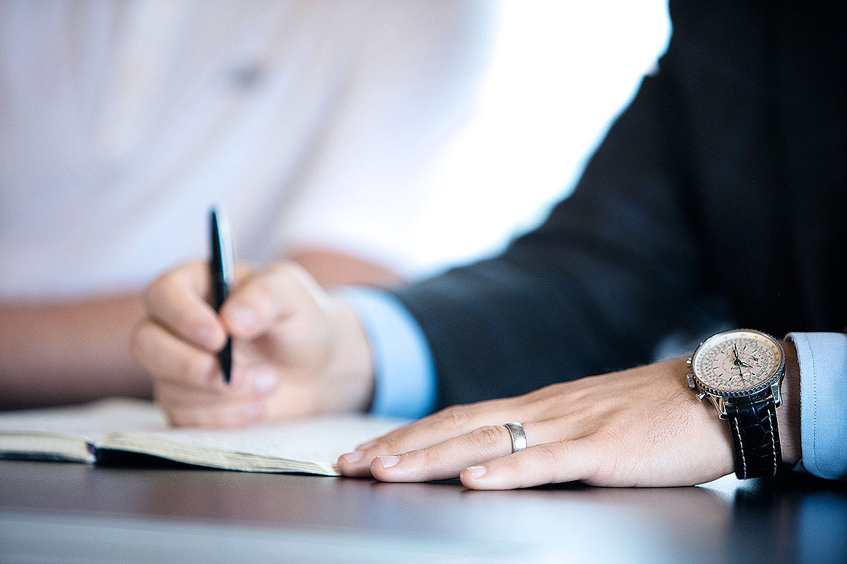 A man writing in a meeting.