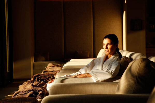 A woman sits in a spa with the sun coming through the window.