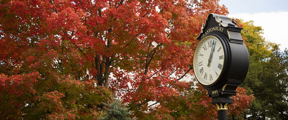 A standing clock with trees behind
