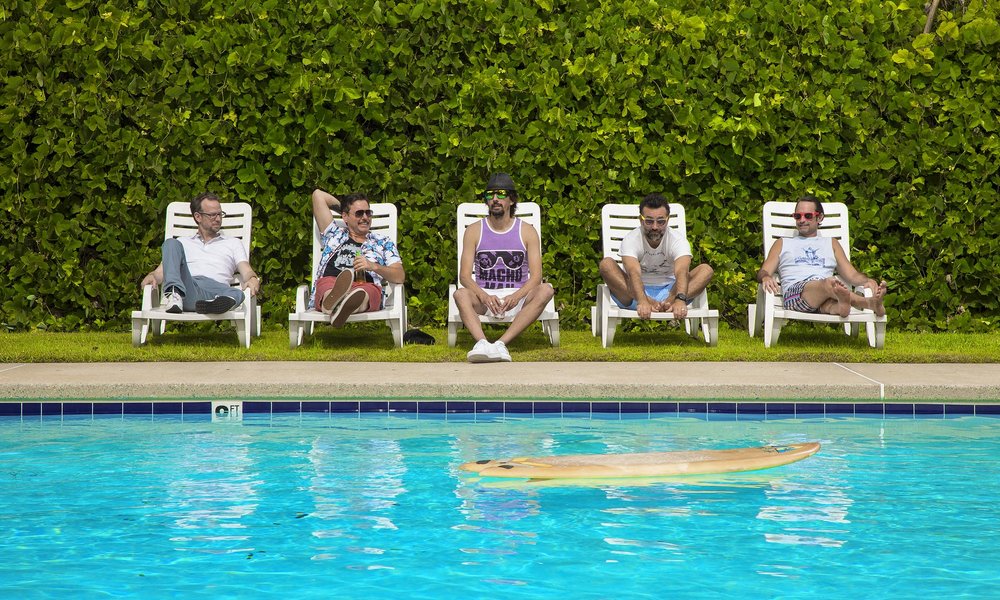 Five men laying in chairs by the pool