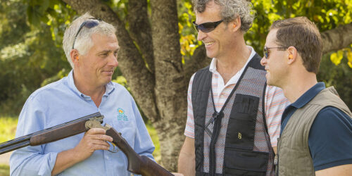 A man displaying a gun to two other men