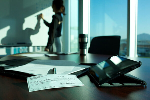 A woman writing on a white board and a check on a desk