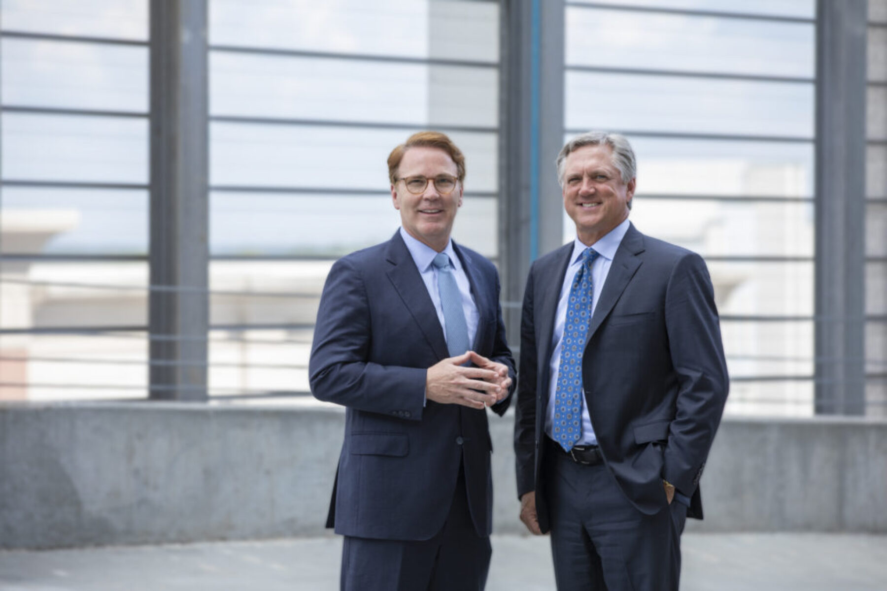 Two men in suits smiling for a photo