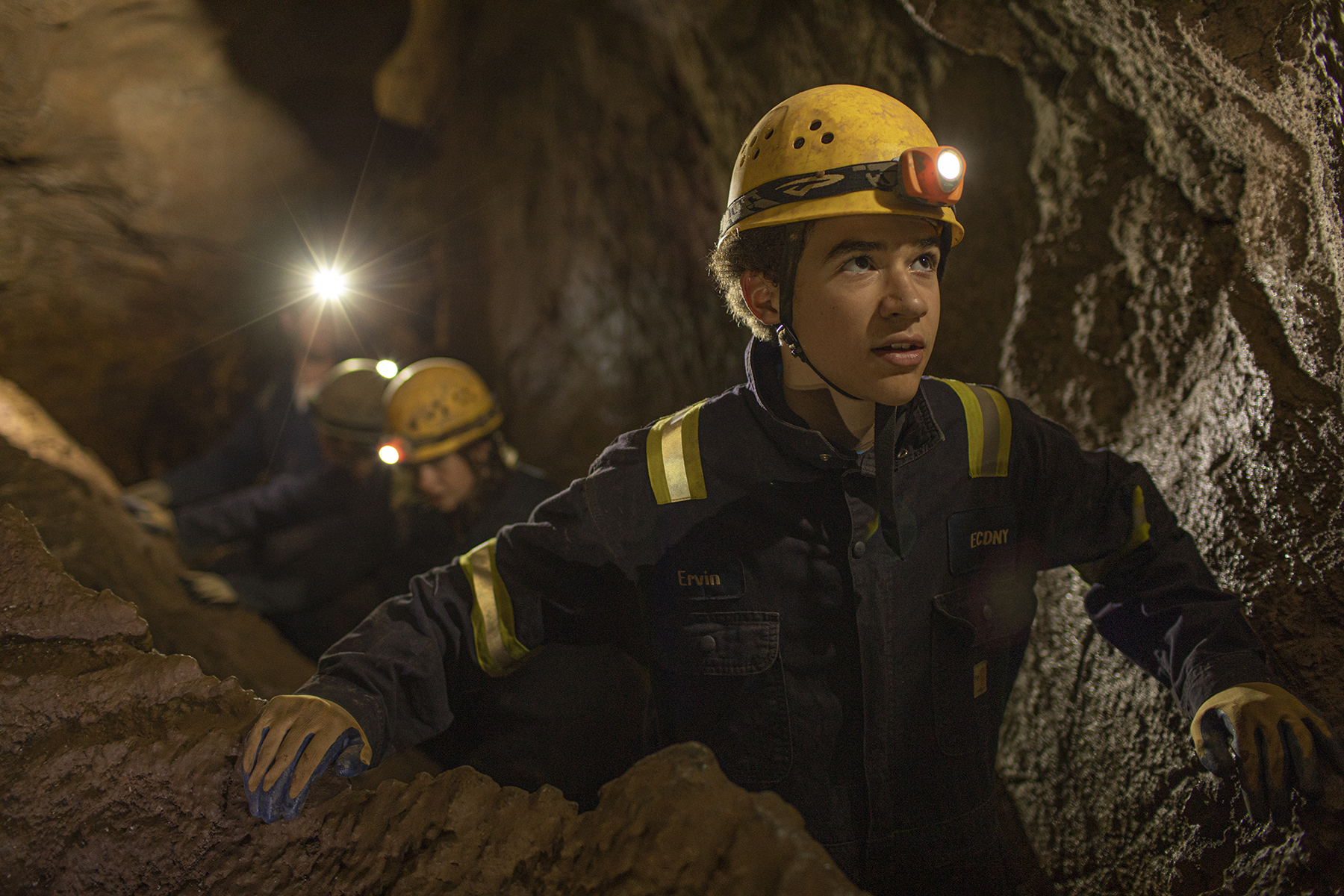 A group of individuals in a single file line inside of a cave