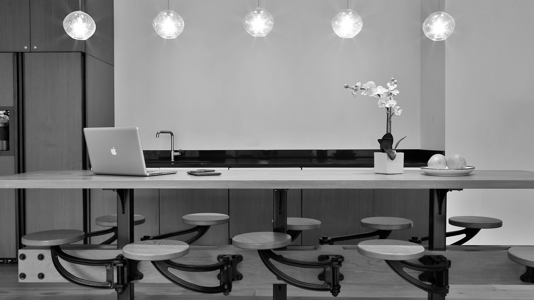 Black and white image of a kitchen with a Macbook and some decorations on a table