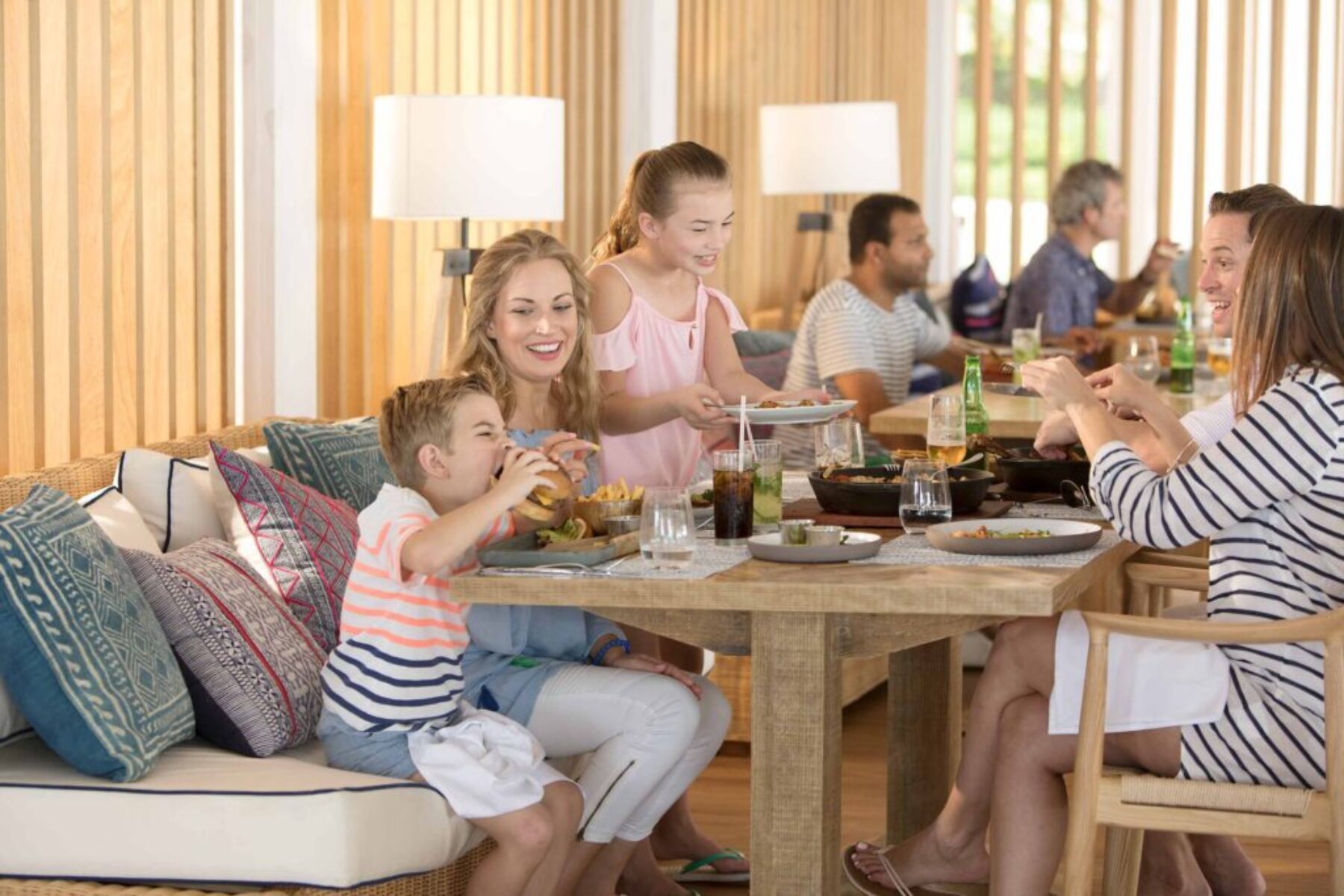 Family enjoying a relaxed meal together at a bright, modern resort restaurant.