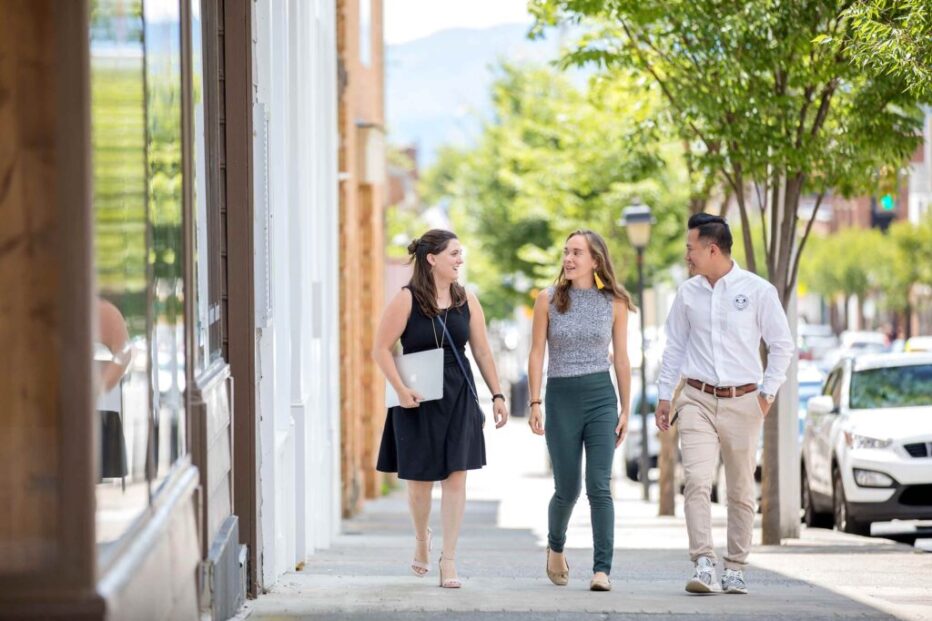 Downtown Professional Lifestyle Photography – Team Walking Three young professionals walking and talking on a sunny downtown sidewalk.