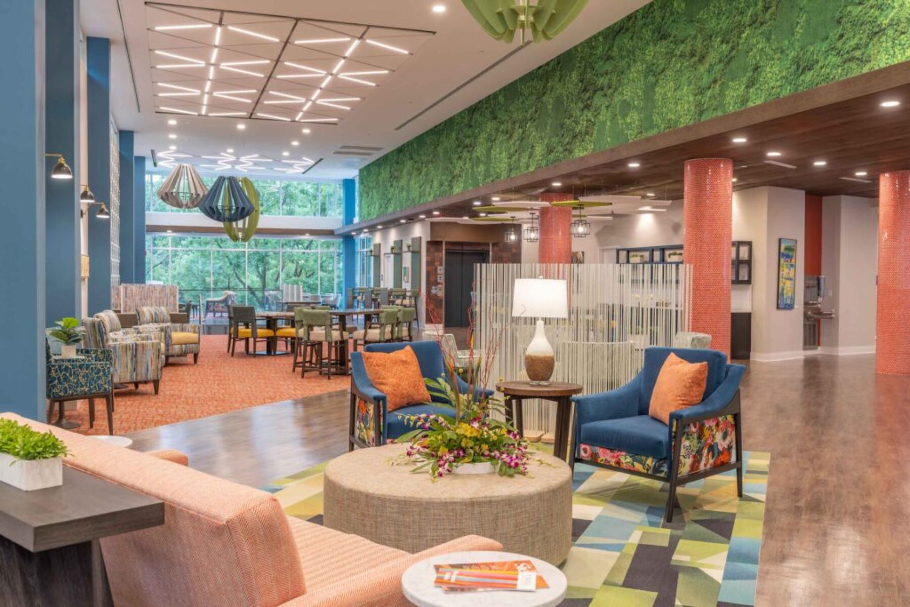 Colorful modern senior living community interior with lounge seating, bright décor, and large windows.