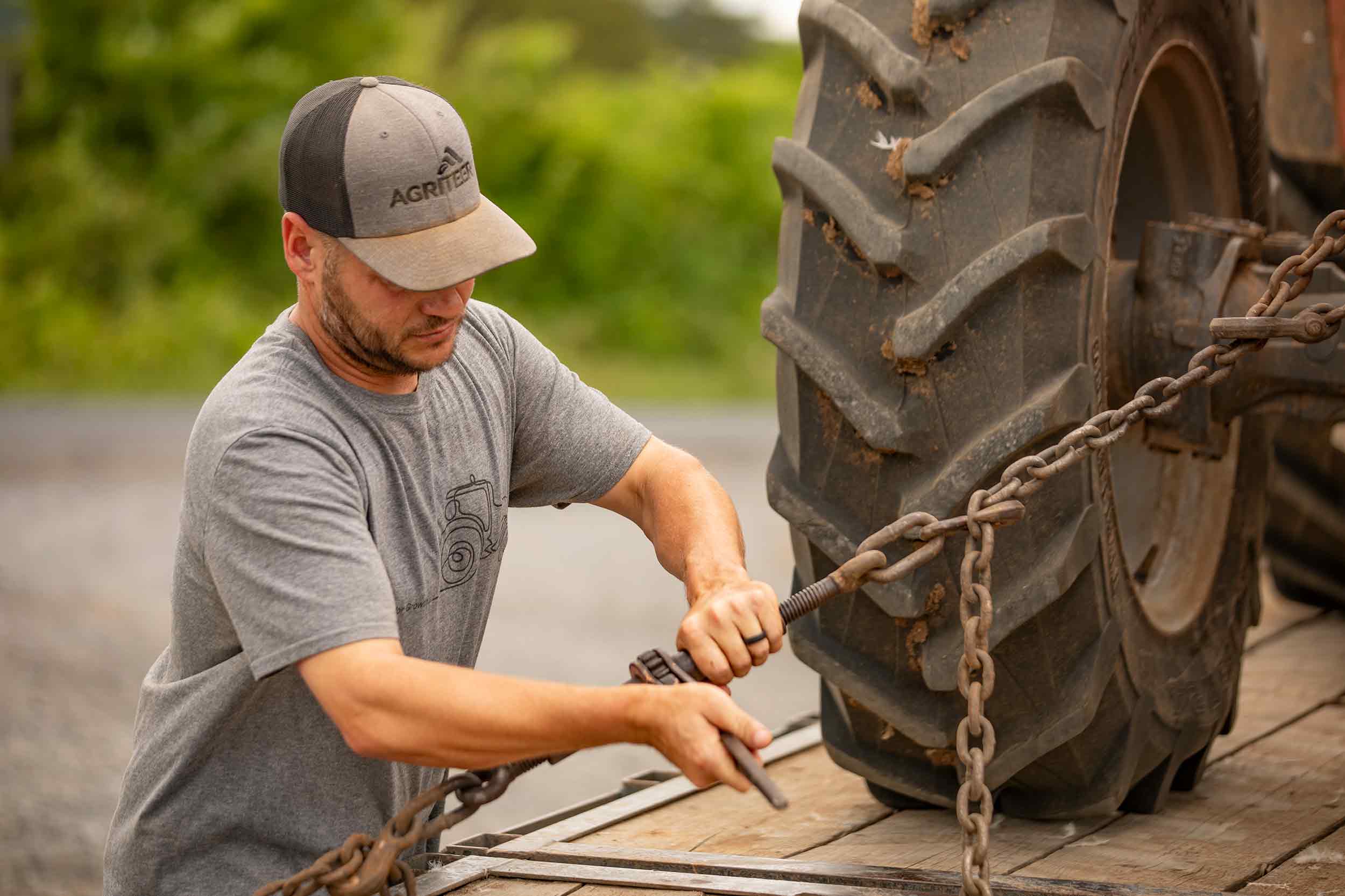 Farmer Focus farmer securing a tractor with chains on a farm trailer.