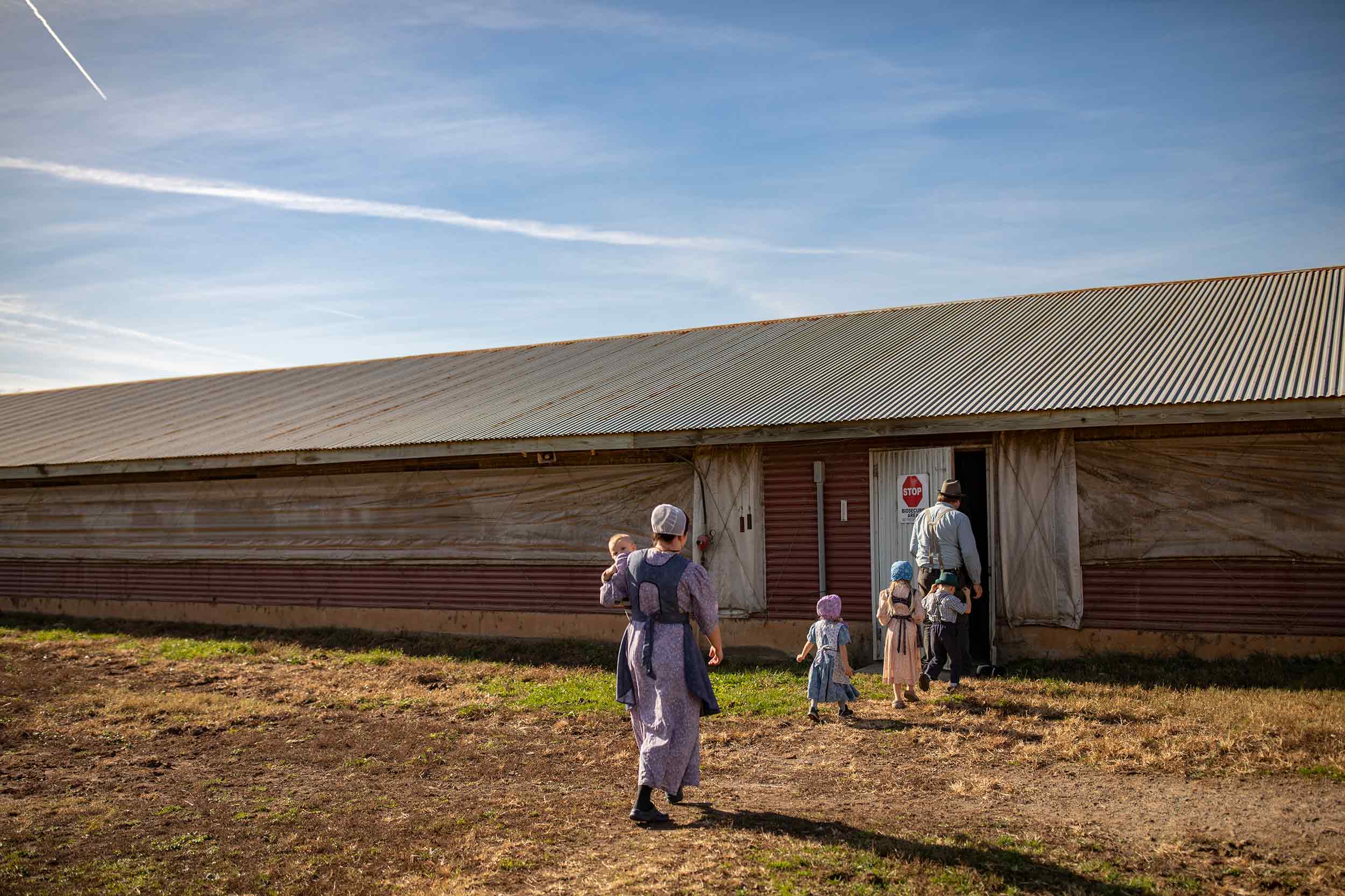Farm family walking toward a poultry house during a Farmer Focus photography shoot.