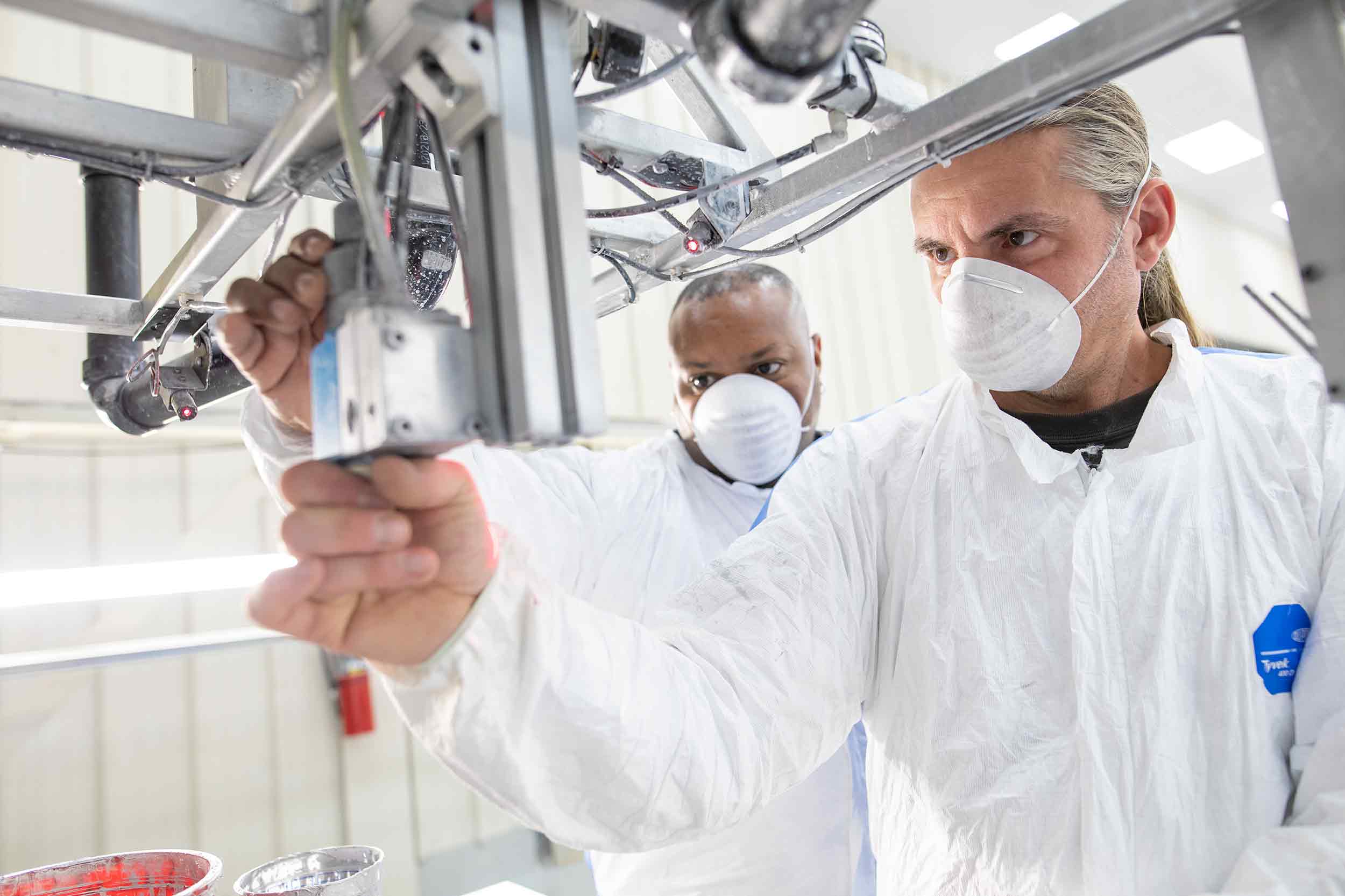 Harkness Screens employees inspecting manufacturing equipment at a Virginia facility.